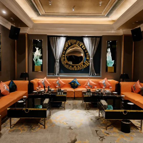 Orange sectional lounge with black tables and gold wall art