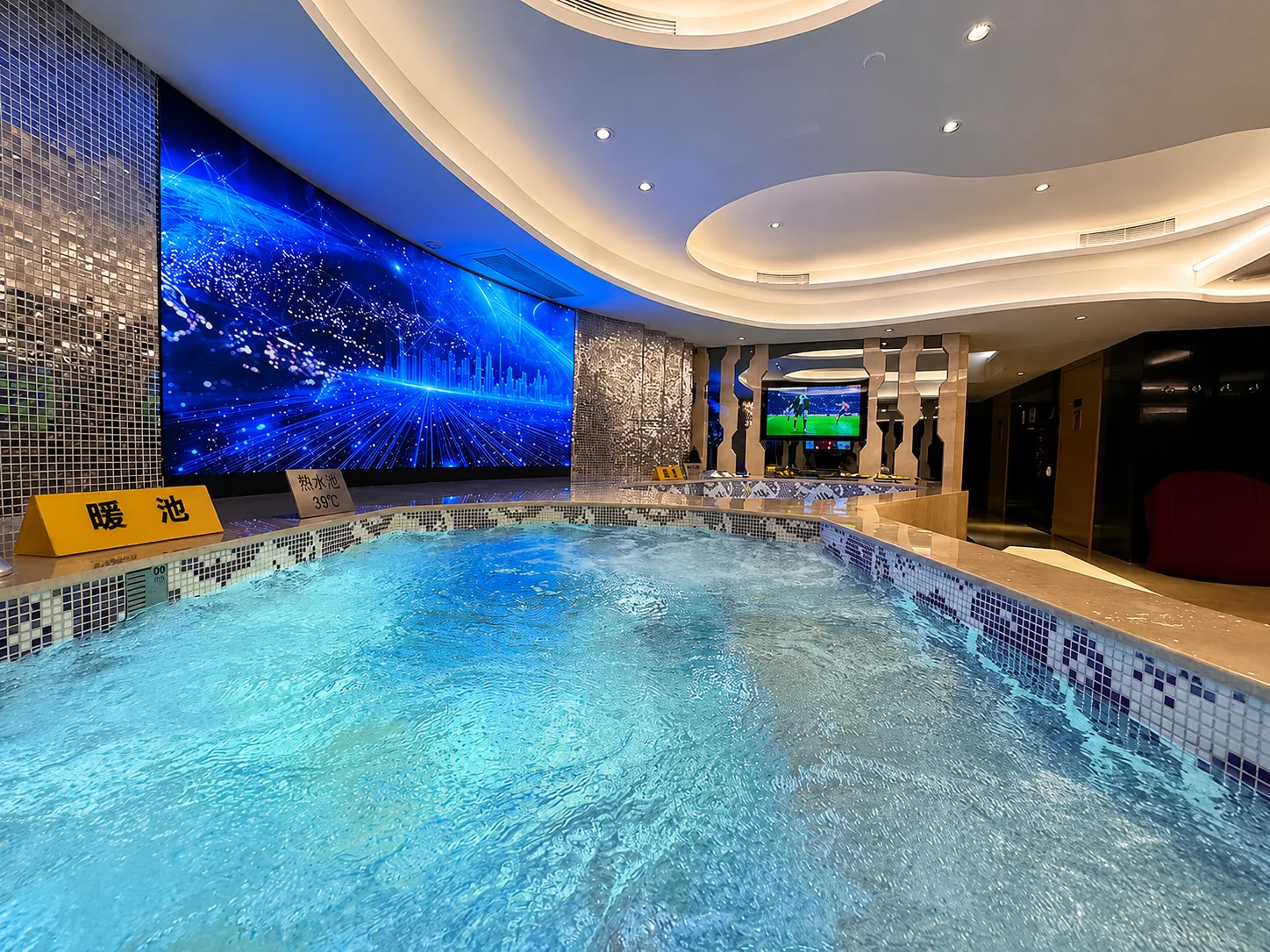 Blue mosaic indoor pool beneath a curved ceiling
