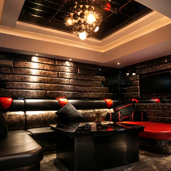 Black and red leather lounge beneath a chandelier