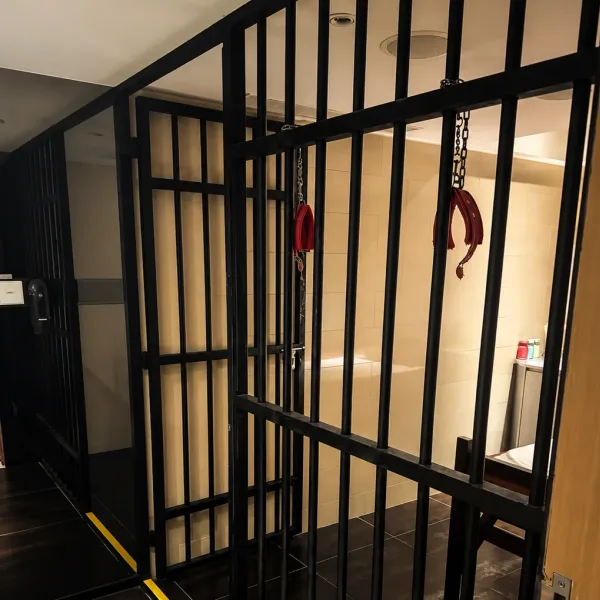 Cell-themed room enclosed by black metal bars