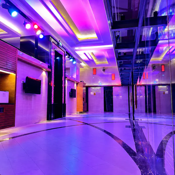 Purple-lit corridor with screens, wood cabinetry and a mirrored wall