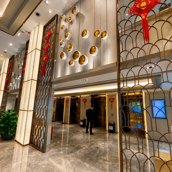 Bright hotel lobby lift area with gold accents and red Chinese knots