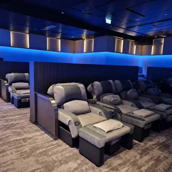Rows of grey recliners under blue ambient lighting
