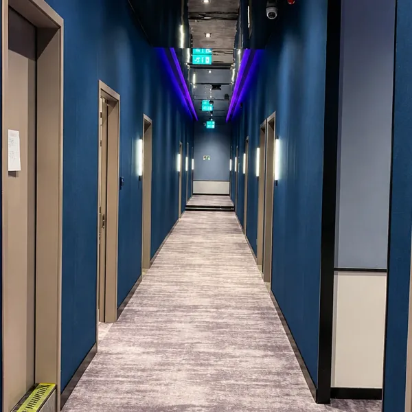 Long blue corridor with wooden doors and purple ceiling lights