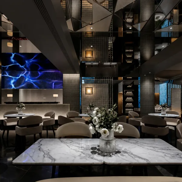 Marble communal table in a dark mirrored dining hall