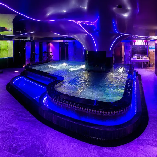 Oval indoor spa pool under purple and blue lights