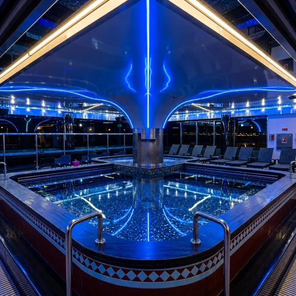 Symmetrical blue-tiled pool beneath an angular mirrored ceiling