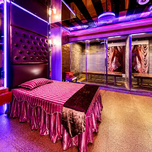Purple-lit bedroom with red upholstered bed and mirrors