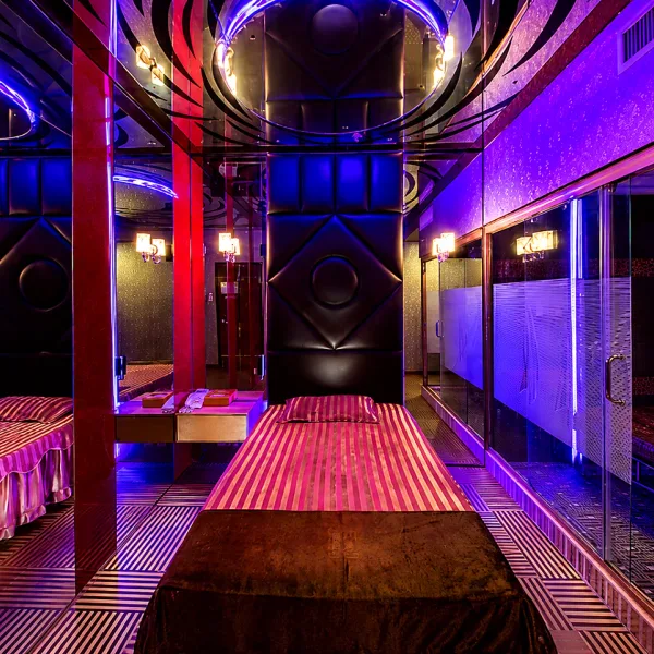 Mirror-lined bedroom with red padded bed and circular ceiling feature