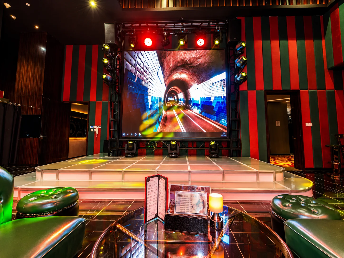 Show stage with large LED screen and green armchairs