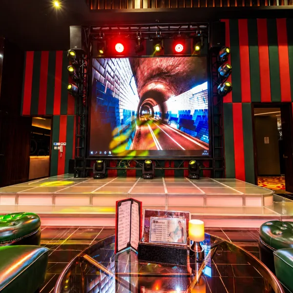 Show stage with large LED screen and green armchairs