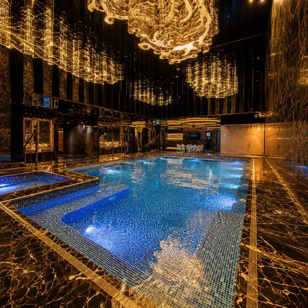 Blue mosaic indoor pool beneath crystal chandeliers