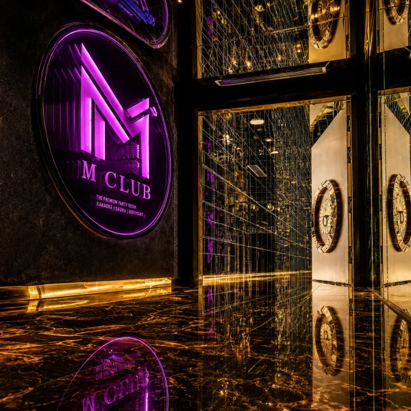 Purple illuminated emblem beside mirrored gold doors