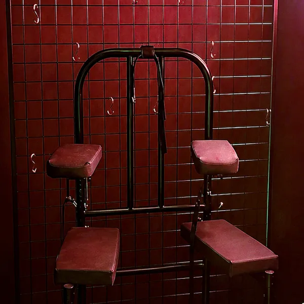 Red padded metal chair against a dark tiled wall