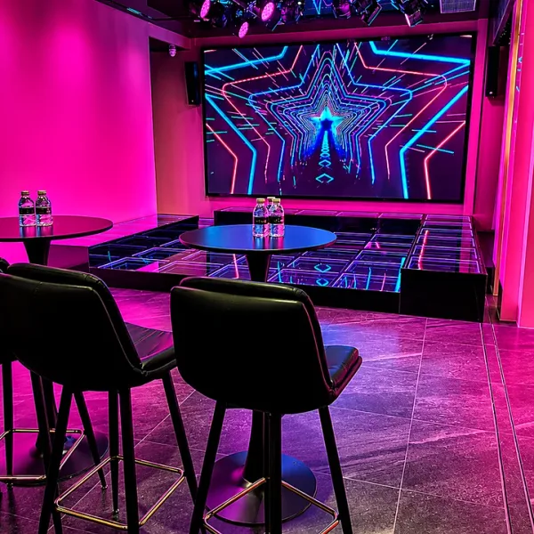 Entrance view of a neon stage room with high tables
