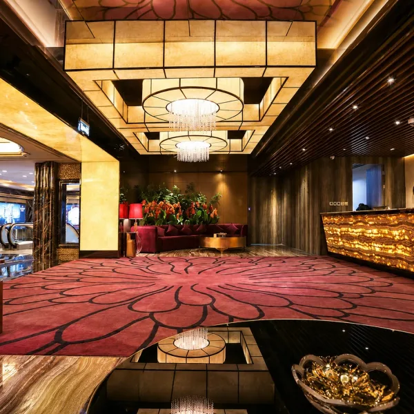 Spacious lobby with red floral carpet and layered ceiling lights