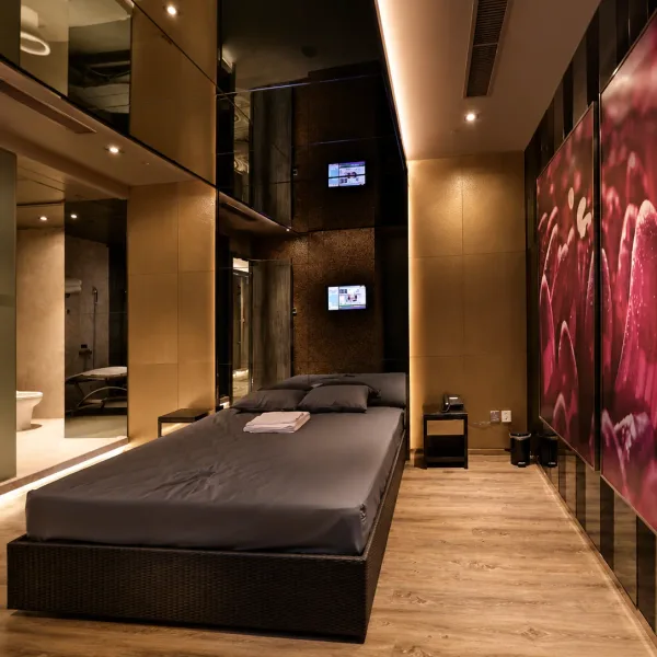 Dark double bed beside a large pink flower mural