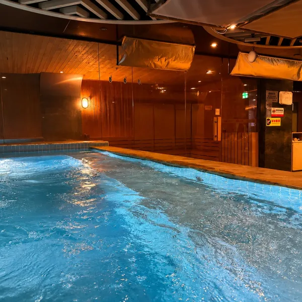 Large blue pool in a wood-panelled bathing room